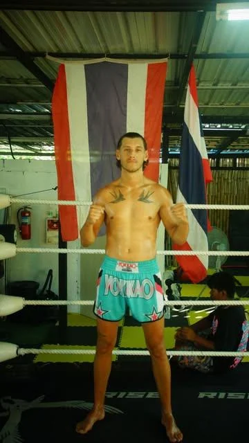 Ein Sportler im Muay-Thai-Gym vor einer thailändischen Flagge